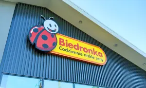 Logo Biedronki z charakterystyczną biedronką na tle nowoczesnej fasady sklepu.