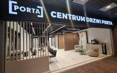 Salon drzwi i okien PORTA z ekspozycją drzwi, meblami i ekspressem do kawy.