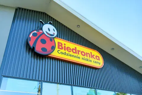 Logo Biedronki z charakterystyczną biedronką na tle nowoczesnej fasady sklepu.