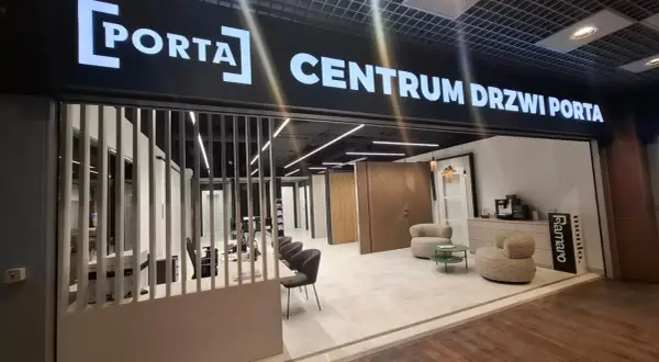 Salon drzwi i okien PORTA z ekspozycją drzwi, meblami i ekspressem do kawy.