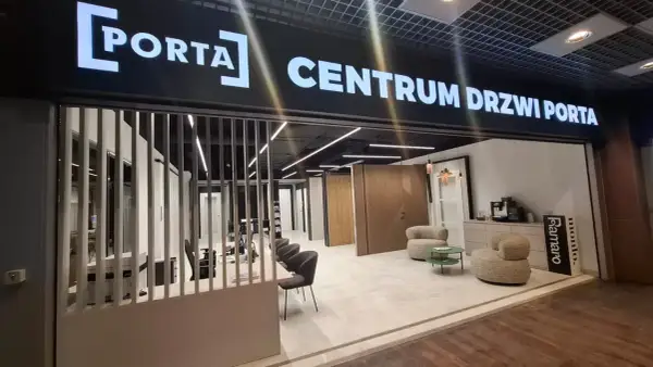 Salon drzwi i okien PORTA z ekspozycją drzwi, meblami i ekspressem do kawy.